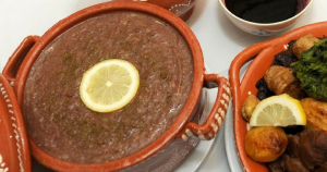Papas espessas servidas em taça de barro com rodela de limão ao lado de prato com carne, batatas e legumes.