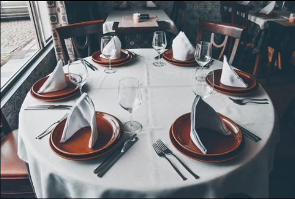 Sala de refeições do Restaurante Roda da Lage com mesas de madeira preparadas com pratos, talheres e copos.
