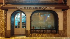 Entrada do Restaurante O Comboio com paredes em pedra, porta envidraçada e toldo com o nome do espaço.