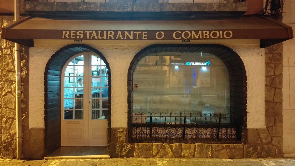 Entrada do Restaurante O Comboio com paredes em pedra, porta envidraçada e toldo com o nome do espaço.