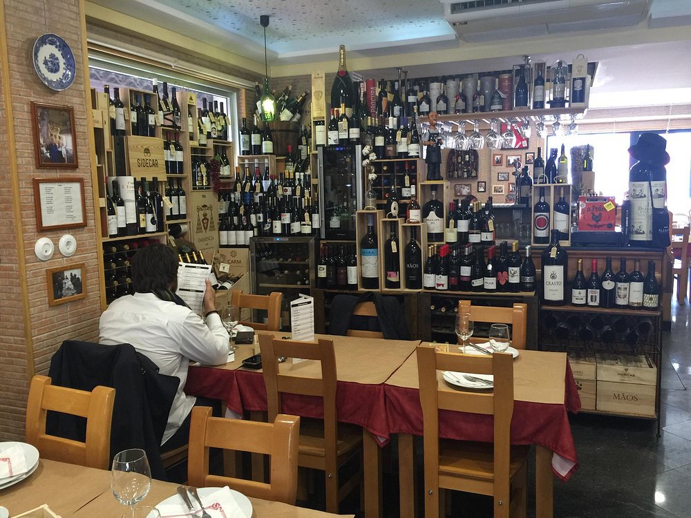 Interior do restaurante D. Pedro com mesas postas e garrafeira repleta de garrafas de vinho.