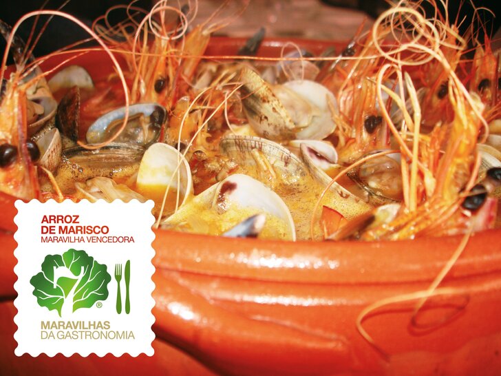 Tacho de barro com arroz de marisco, incluindo camarões, amêijoas e mexilhões; à esquerda vê‑se um rótulo com texto.