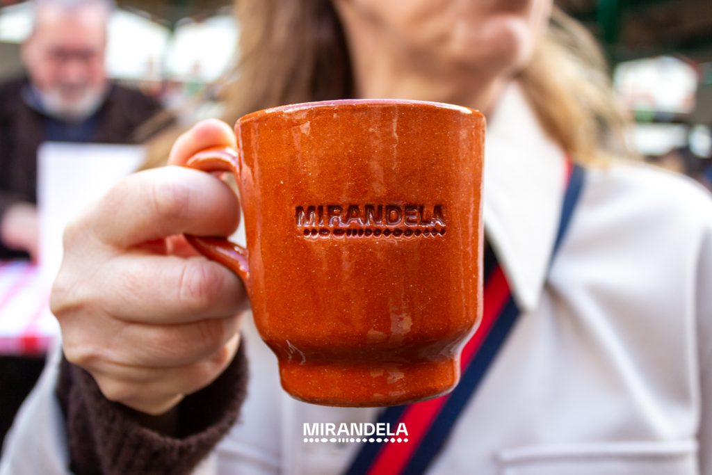 Caneca castanha com a palavra “Mirandela” em relevo, segurada por uma pessoa.