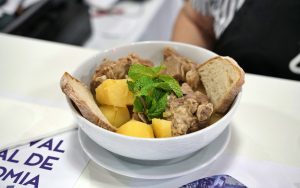 Tigela com carne, batatas e fatias de pão, decorada com folhas de hortelã.