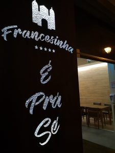 Letreiro iluminado com o nome “Francesinha É Prá Sé” sobre a entrada do restaurante, com interior visível ao fundo.