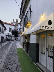 Fachada exterior do Restaurante O Pote com toldo branco, em rua pitoresca de calçada portuguesa em Arcos de Valdevez.