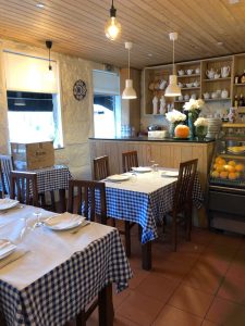 Sala de restaurante com mesas cobertas por toalhas axadrezadas azuis e brancas, cadeiras de madeira e iluminação quente.