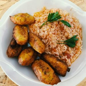 Prato branco com arroz avermelhado decorado com salsa e acompanhamento frito dourado.