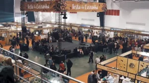 Salão de exposições da Festa da Castanha com dezenas de estandes organizados em corredores, visitantes circulando e faixas suspensas do evento.
