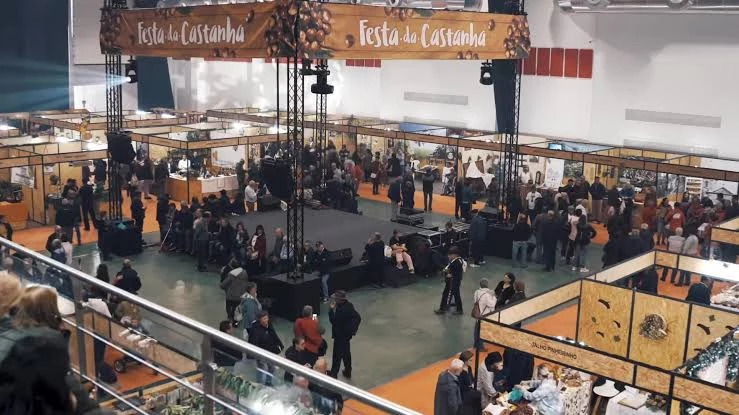 Salão de exposições da Festa da Castanha com dezenas de estandes organizados em corredores, visitantes circulando e faixas suspensas do evento.