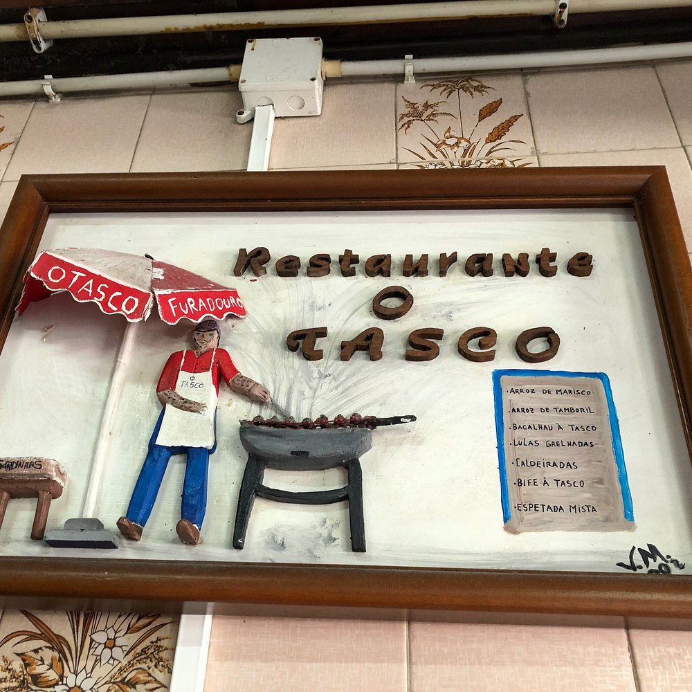 Placa decorativa com figura a grelhar alimentos e lista de pratos do Restaurante O Tasco.