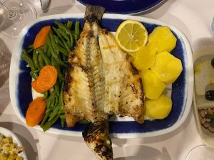 Peixe grelhado aberto ao meio, servido com batatas cozidas, feijão‑verde, cenoura e uma rodela de limão num prato retangular.