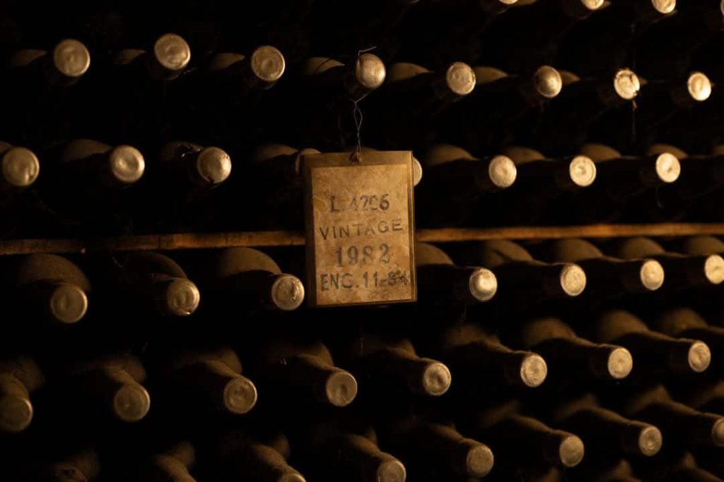 adega tradicional, com várias garrafas de vinho envelhecendo em prateleiras.