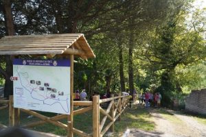 Placa coberta exibe mapa do “Parque de Merendas da Ponte Trilho Caminhos das Azenhas”, cercada por árvores e visitantes em trilha.