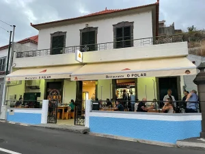 principal: Fachada do Restaurante O Polar, com varanda, mesas ocupadas por clientes, pessoas no interior, toldos e prédio colonial de dois andares