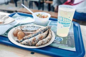 Prato com sardinhas grelhadas, batatas cozidas, salada e copo com logótipo do Festival da Sardinha de Portimão.